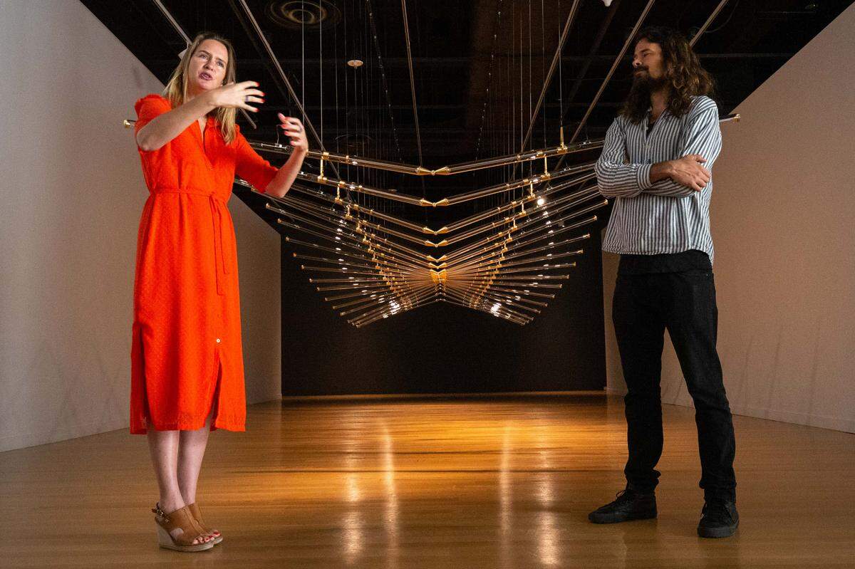 Lonneke Gordijn, left, and Ralph Nauta of Studio Drift talk about their piece called “Amplitude.” Gordijn says the piece on display at the Mint Museum Uptown expresses the fundamental steps in nature of movement in our evolutionary process.