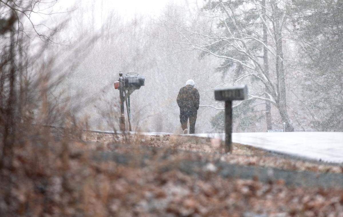 A resolute pedestrian strides through the heavy snowfall along North Carolina Highway 73 on Wednesday, February 19, 2025.