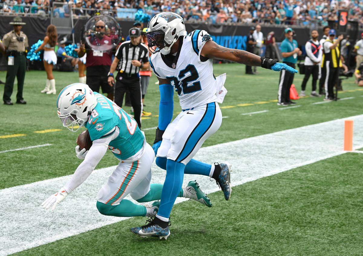 Miami Dolphins running back De'Von Achane, left, falls to the turf after catching a pass in the end zone as Carolina Panthers linebacker Trevin Wallace, right, applies pressure during action on Sunday, October 5, 2025 at Bank of America Stadium in Charlotte, NC.