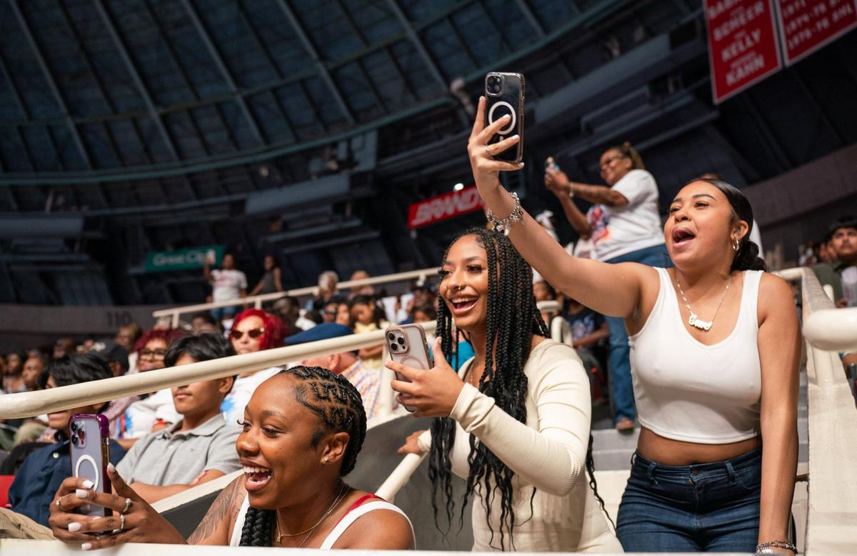 Friends of an Olympic High School graduate cheer and record during the graduation ceremony at the Bojangles Coliseum in Charlotte on Monday, June 10, 2024.