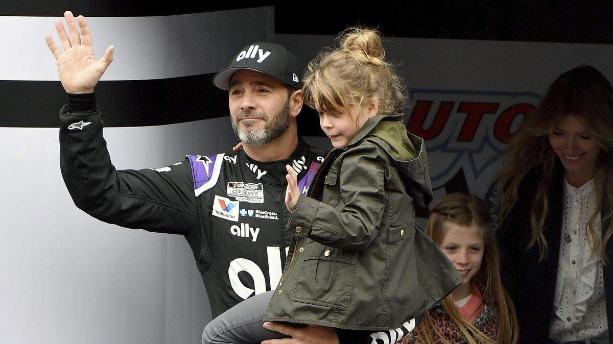 FILE - In this March 1, 2020, file photo, Jimmie Johnson is introduced to the crowd during activities as he carries his youngest daughter Lydia as his oldest daughter Genevieve and wife Chandra follow prior to a NASCAR Cup Series auto race in Fontana, Calif. Jimmie Johnson wanted to retire from full-time racing to step away from NASCAR’s 11-month grind. The coronavirus pandemic has brought his final season to an unexpected pause, and now the seven-time champion isn’t sure what his future holds. (AP Photo/Will Lester, File)