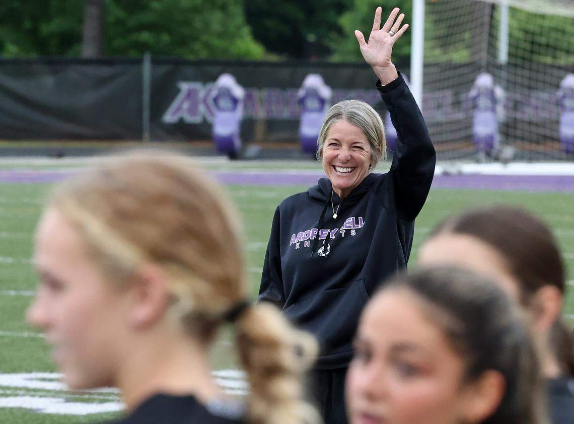 Ardrey Kell girls soccer coach Kim Montgomery, center, smiles as she waits for action to begin against Ballantyne Ridge on Tuesday, April 28, 2026. Ardrey Kell defeated Ballantyne Ridge 1-0.