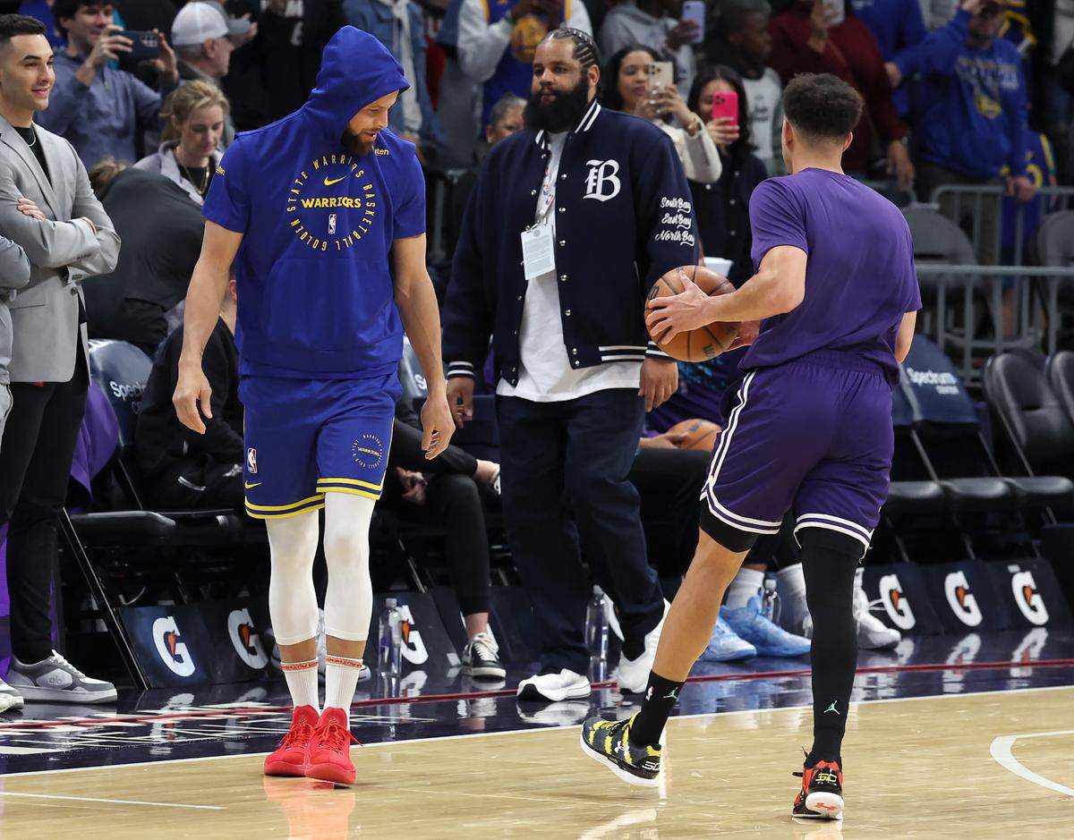 Golden State Warriors and former Davidson Wildcats star Steph Curry, left, looks at his brother, Seth Curry’s, right, shoes as he walks onto the court prior to the team’s game against the Charlotte Hornets at Spectrum Center in Charlotte, NC on Monday, March 3, 2025.
