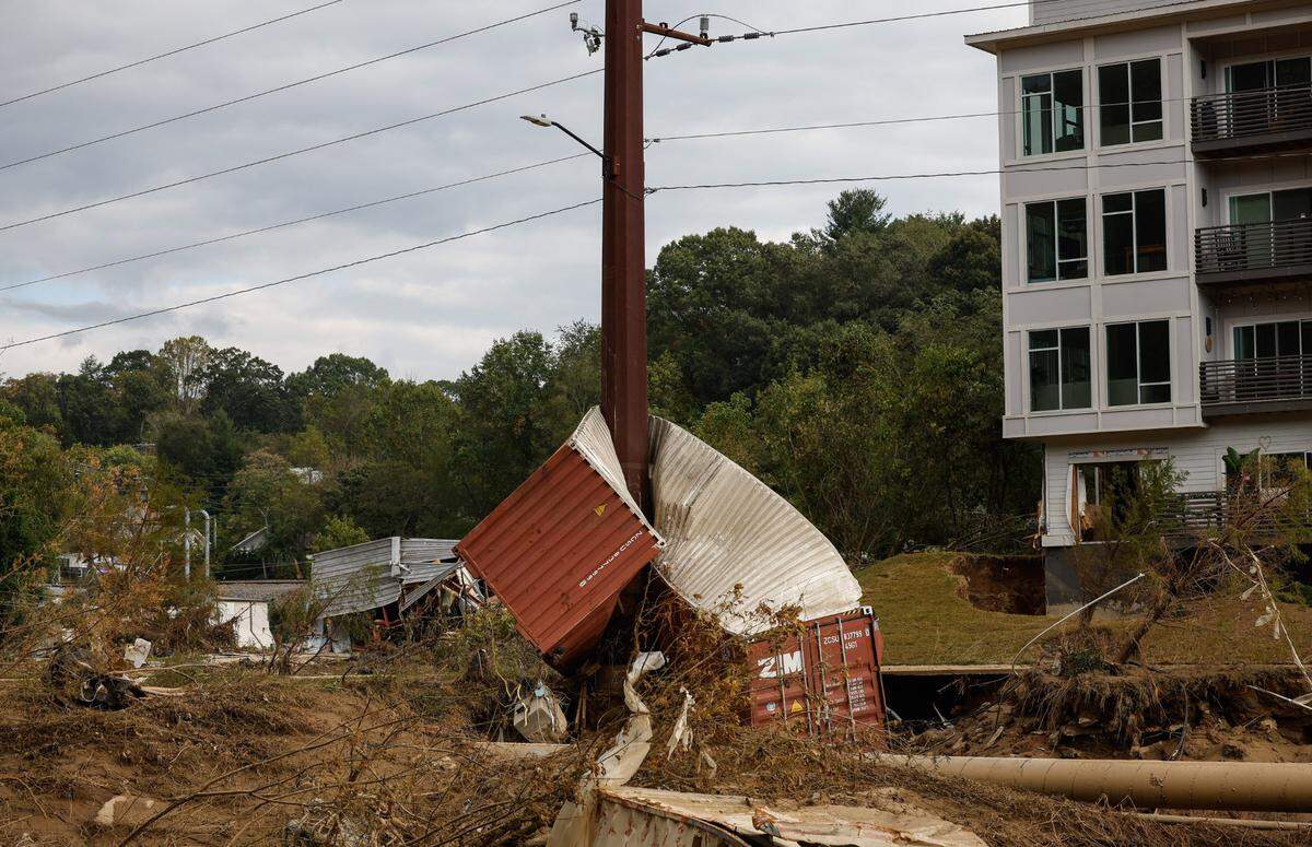 A shipping container wrapped around a Duke Energy transmission tower along the Swannanoa River, near Biltmore Village, in Asheville on Thursday, Oct. 3, 2024.