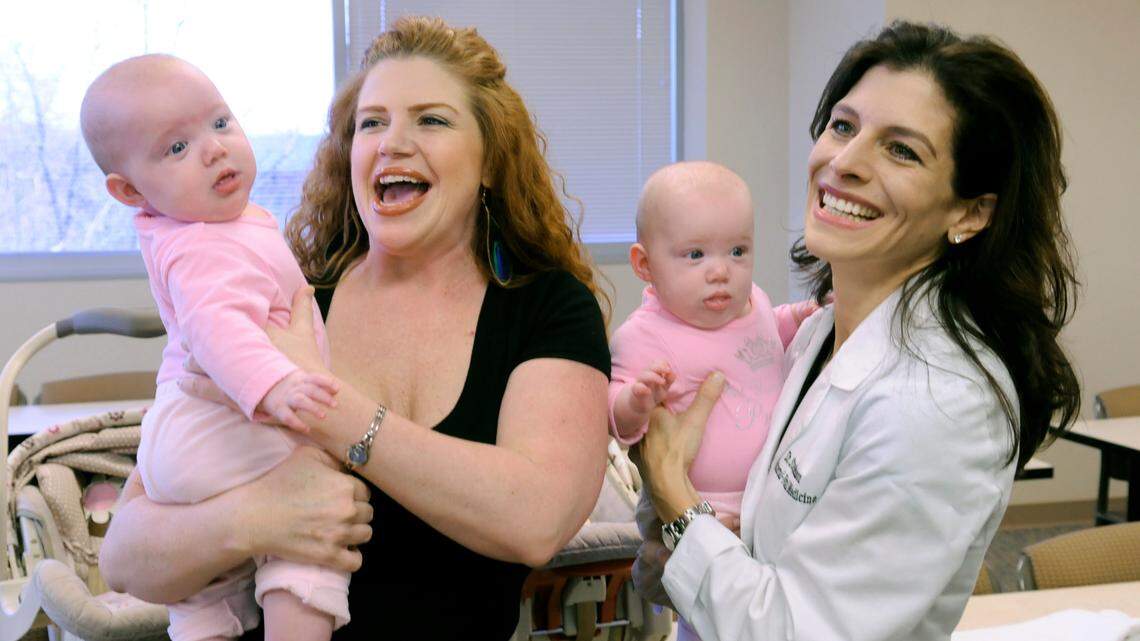 Charlotte prenatal surgeon Courtney Stephenson, shown in 2010 with two of her identical-twin patients and their mother, has sued Atrium Health, alleging that her firing in 2019 was illegal. She is asking for $10 million in damages.