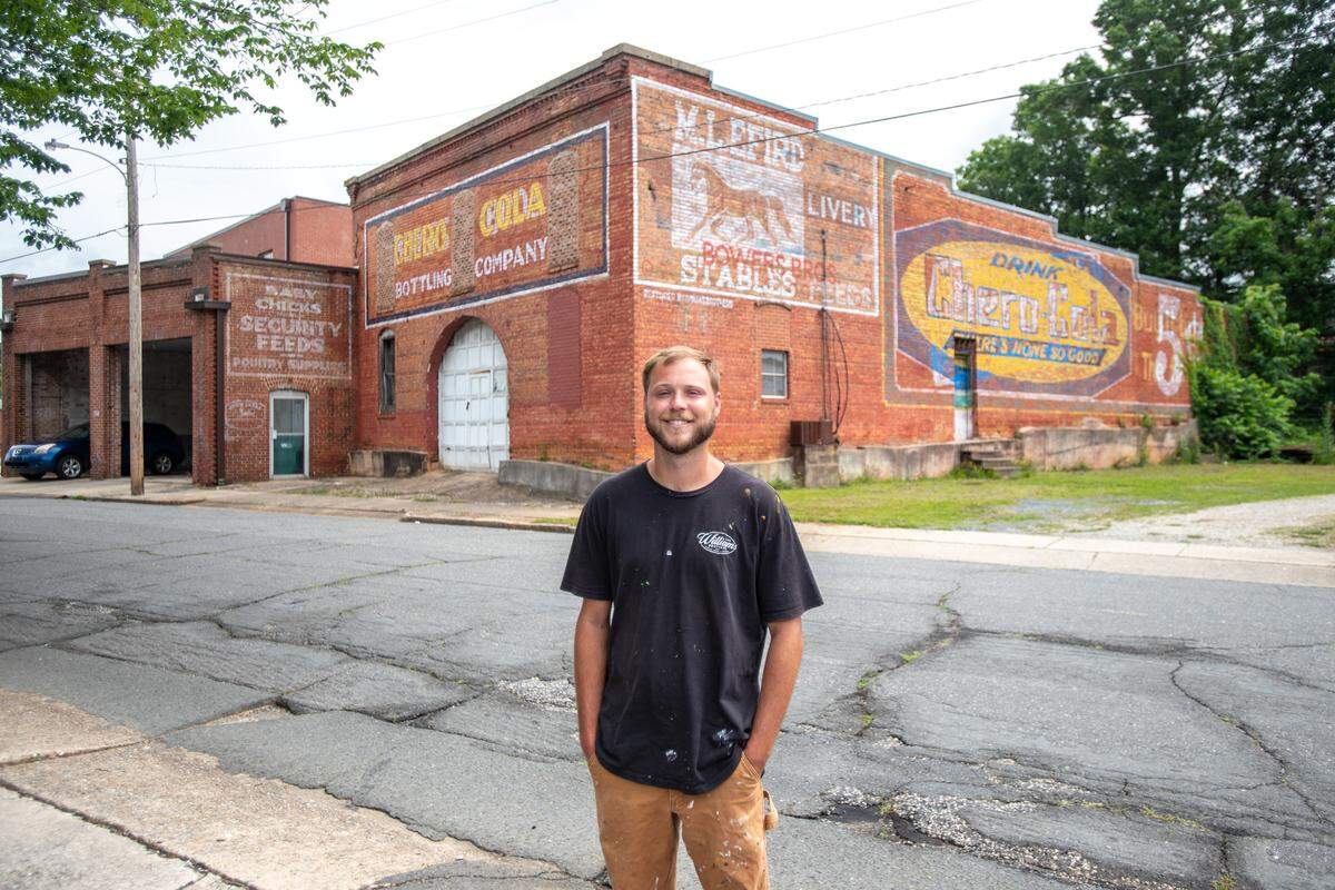 Albemarle native and muralist Jack Williams poses in front of his work on N. Depot Street in Albemarle. Jack and his brother Eli returned to live in Albemarle after completing their respective art degrees and manage their business, WMSBrothers.