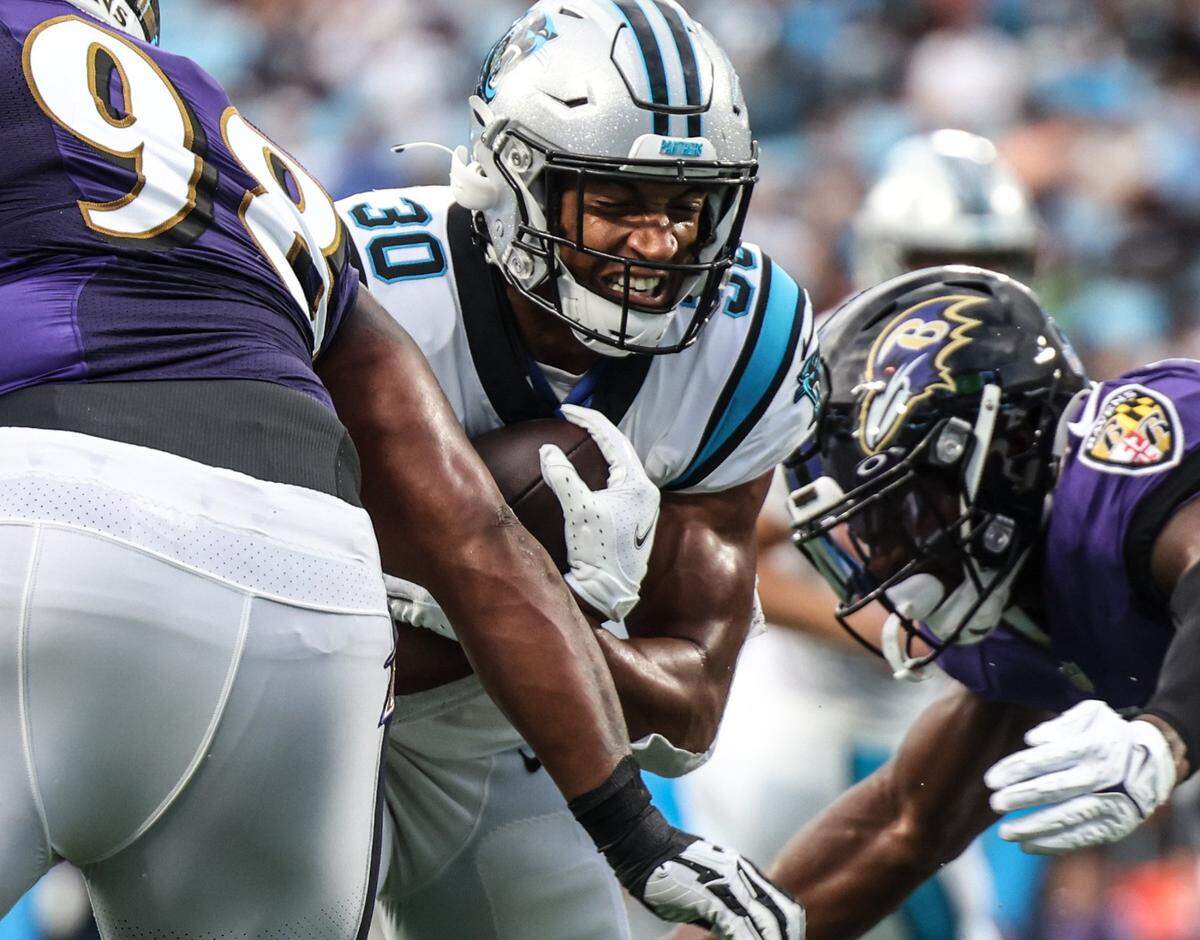Carolina Panthers Chuba Hubbard, center, runs through Baltimore Ravens Brandon Williams, left, and at the Bank of America Stadium in Charlotte, N.C., on Saturday, August 21, 2021.