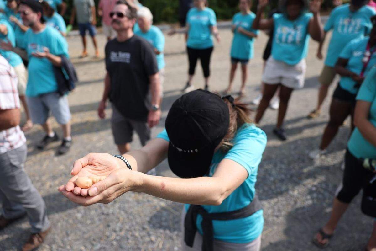 A woman extends a representation of a miniature baby in her hands outside a Charlotte abortion clinic in Charlotte, June 25, 2022.