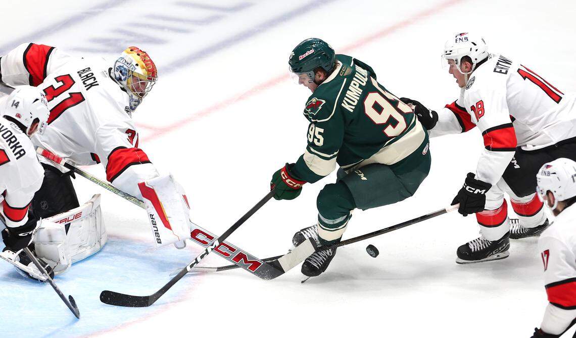 Charlotte Checkers goalie Cooper Black, left, is able to knock the puck away from the Iowa Wild’s Rasmus Kumpulainen, center, as he nears the goal during second period action on Friday, October 17, 2025 at Bojangles Coliseum in Charlotte, NC. 