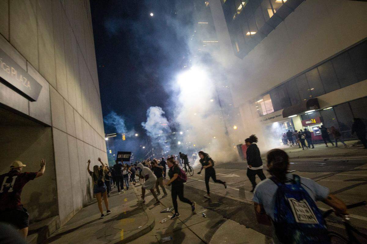 Protesters scramble on 4th Street as police fire chemical agents on either side of the marchers in uptown Charlotte, NC on Tuesday, June 2, 2020.