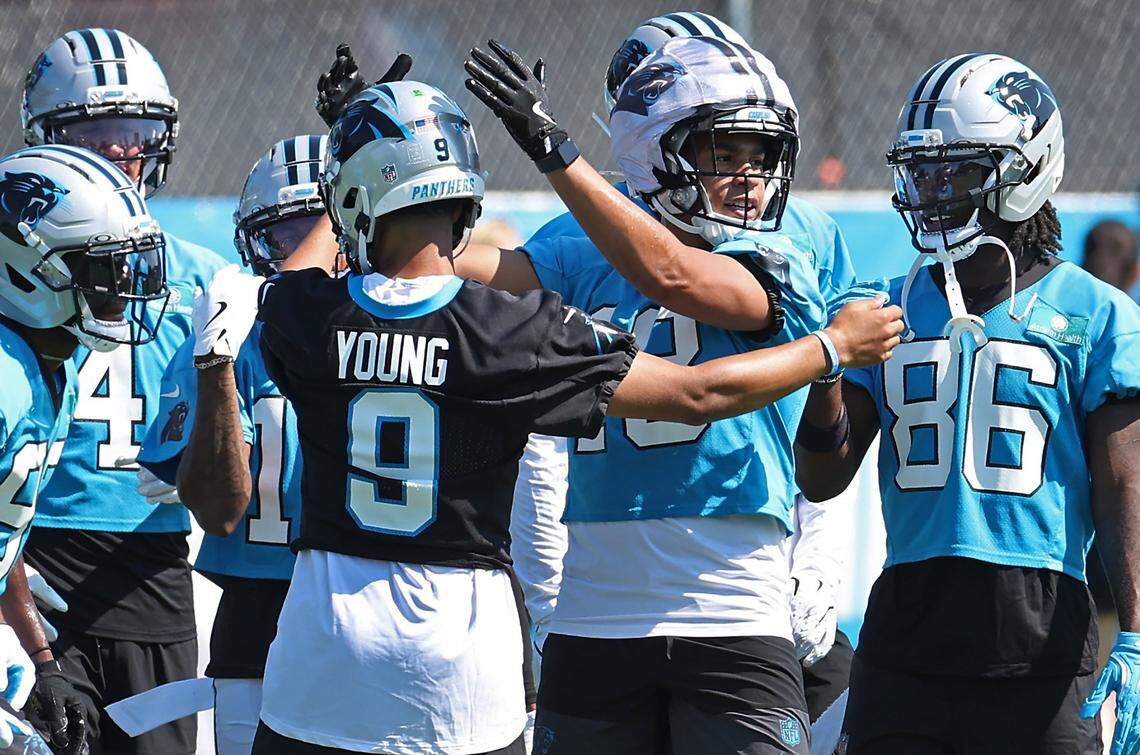 Carolina Panthers quarterback Bryce Young, back to camera and wide receiver Jalen Coker, right, come together with their teammates following a series of drills during a training camp practice on Wednesday, July 23, 2025. 