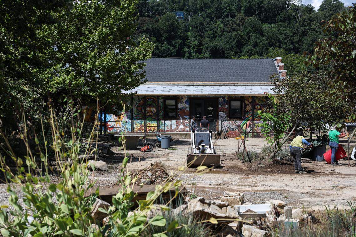 People work on cleaning up the River Arts District in Asheville, which experienced historic and devastatting flooding during Helene last year.