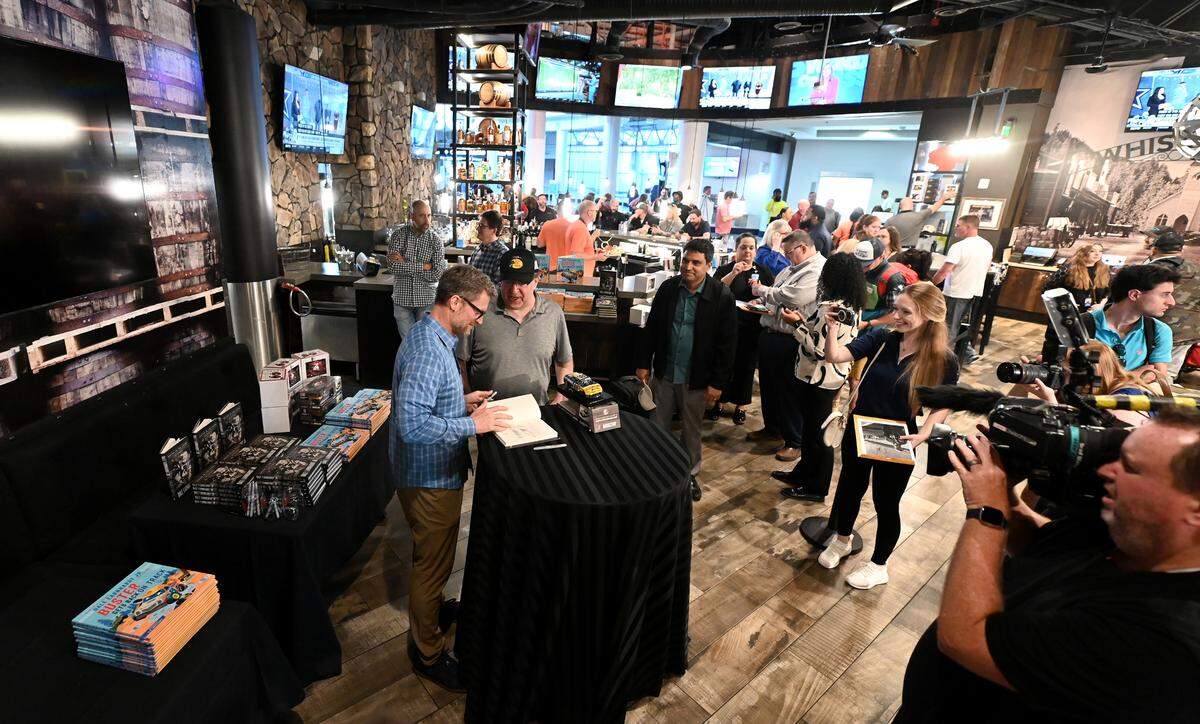 Former NASCAR driver Dale Earnhardt Jr., left, signs a copy of his books Racing to the Finish: My Story and children’s book Buster Gets Back on Track on Thursday, October 5, 2023 at his Whisky River restaurant located at Charlotte Douglas International Airport.