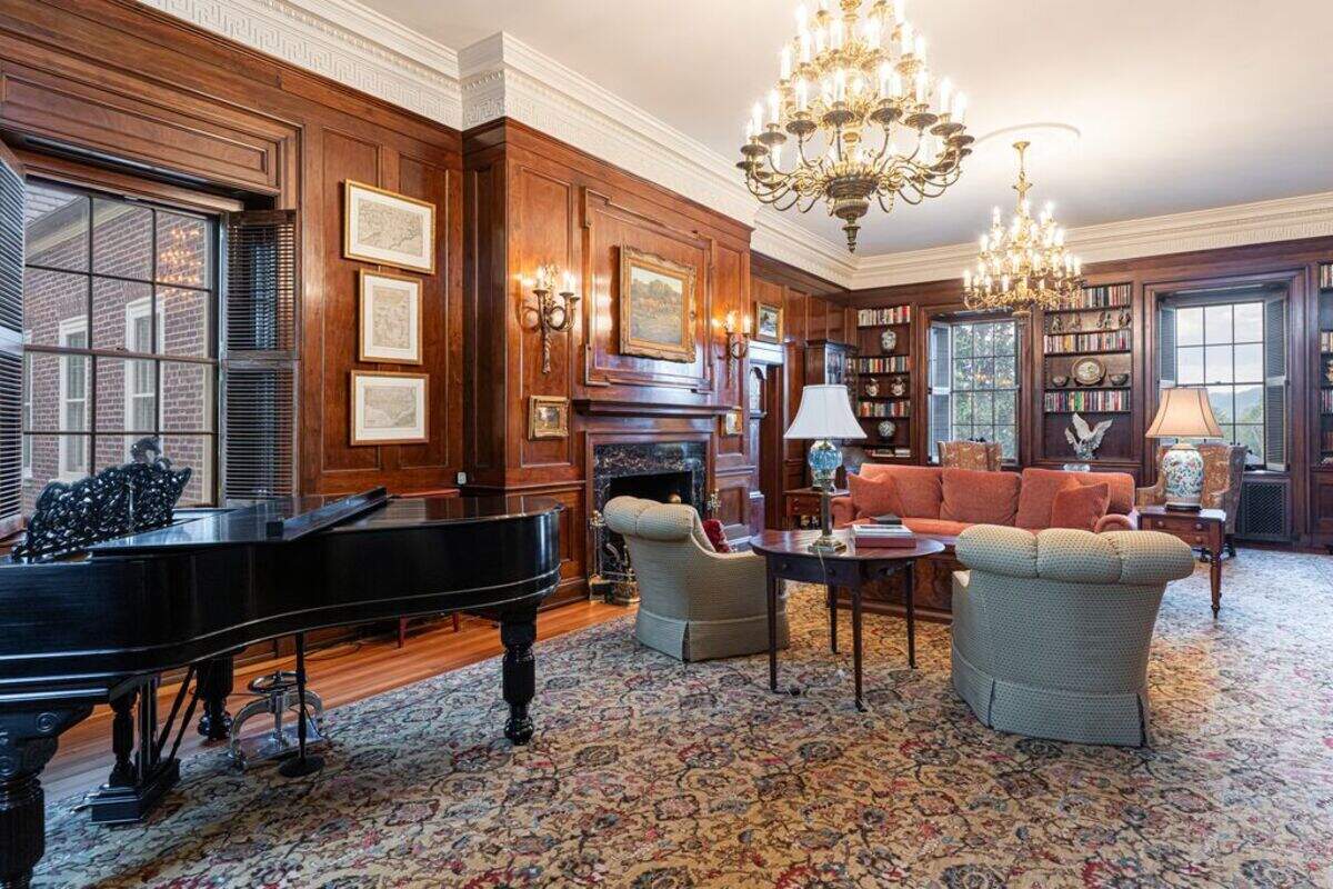 This parlor in the mansion features chandeliers and a grand piano.