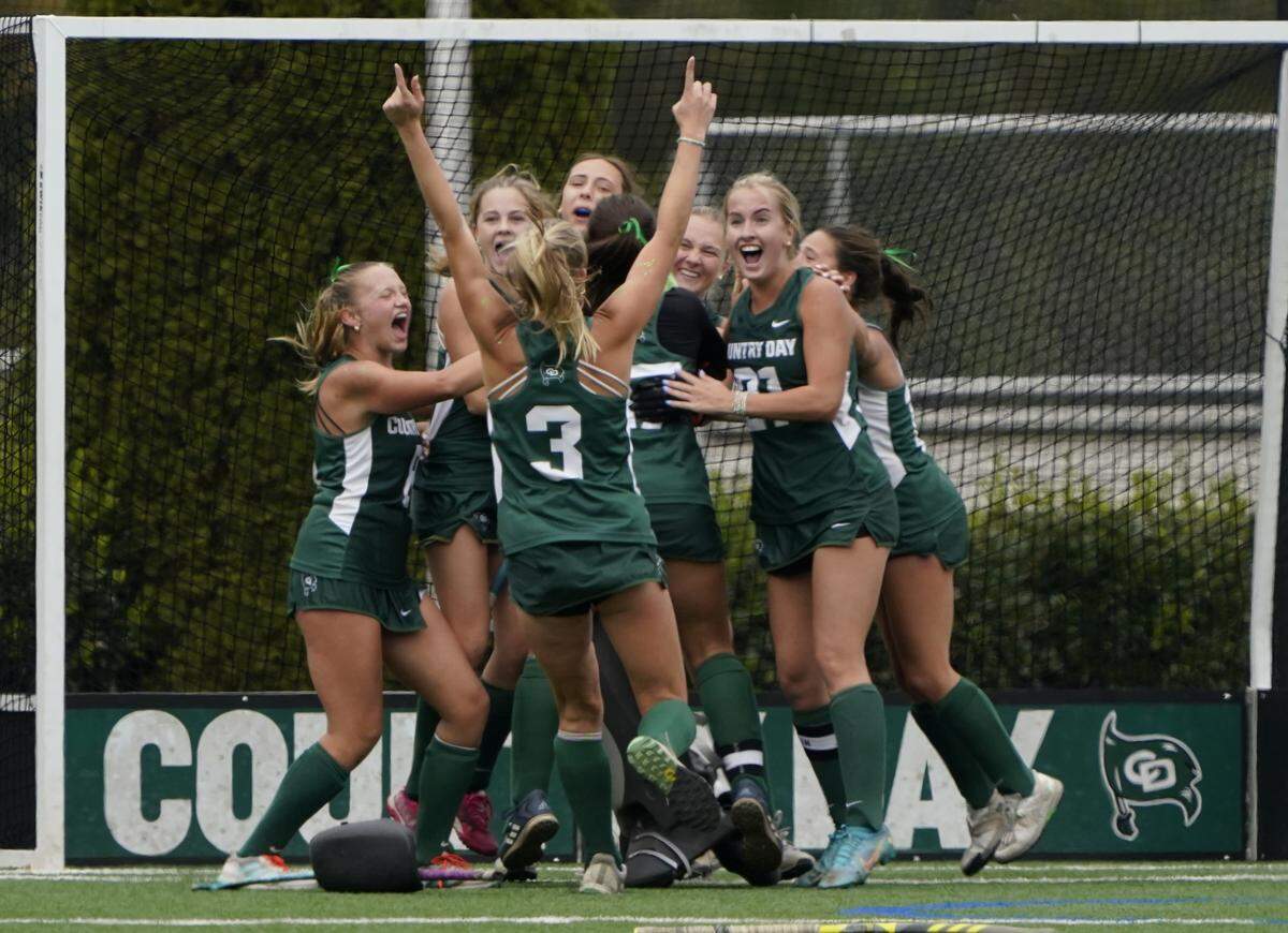 Charlotte Country Day's Katy Blythe shows who's No. 1 as her teammates celebrate following the Buccaneers' 1-0 victory over Charlotte Latin in Saturday's NCISAA field hockey state championship game.