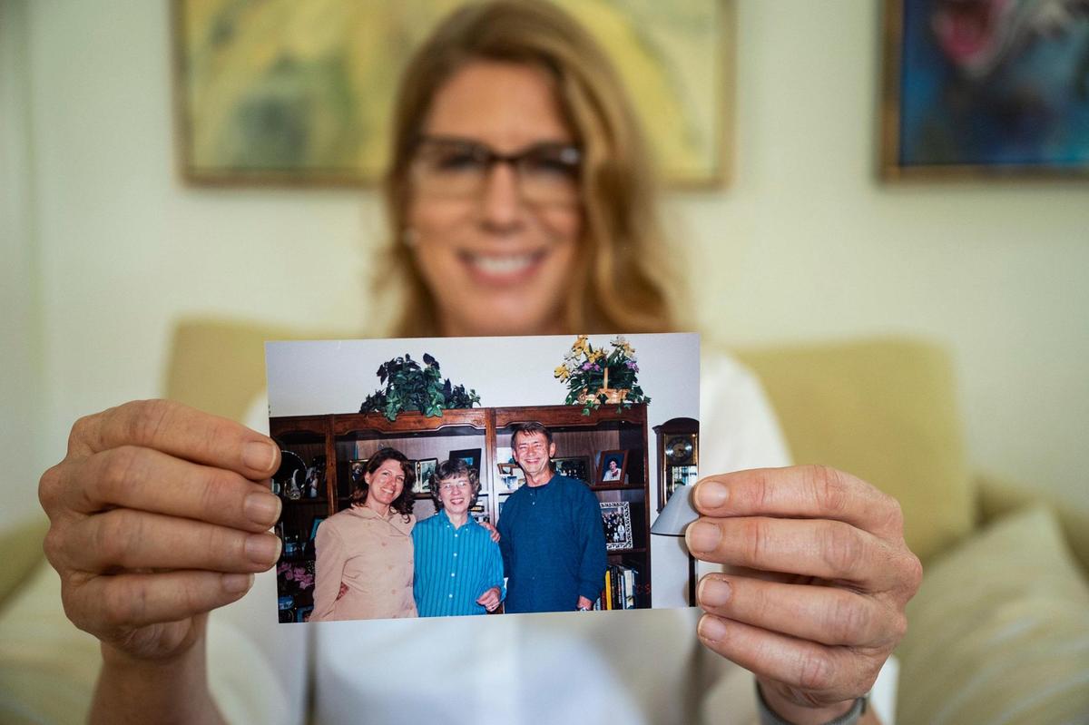 Jenna MacFarlane holds a photo of the day she met her “adoptive” parents, Steve and Karen Kesler.