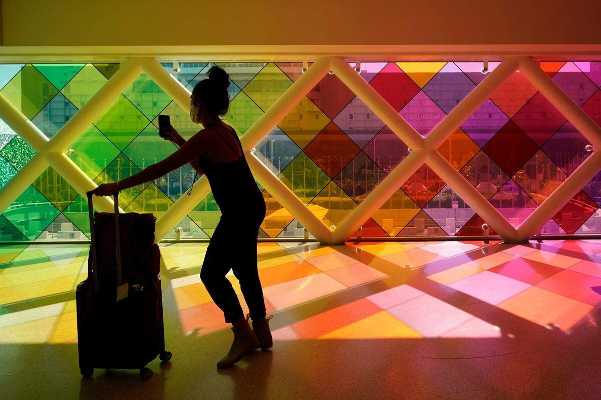 A traveler takes photos of windows titled “Harmonic Convergence” at Miami International Airport in May 2021. Police in Miami arrested and charged a man with Charlotte ties after a woman was choked with a shoelace and beaten at an airport bus stop.