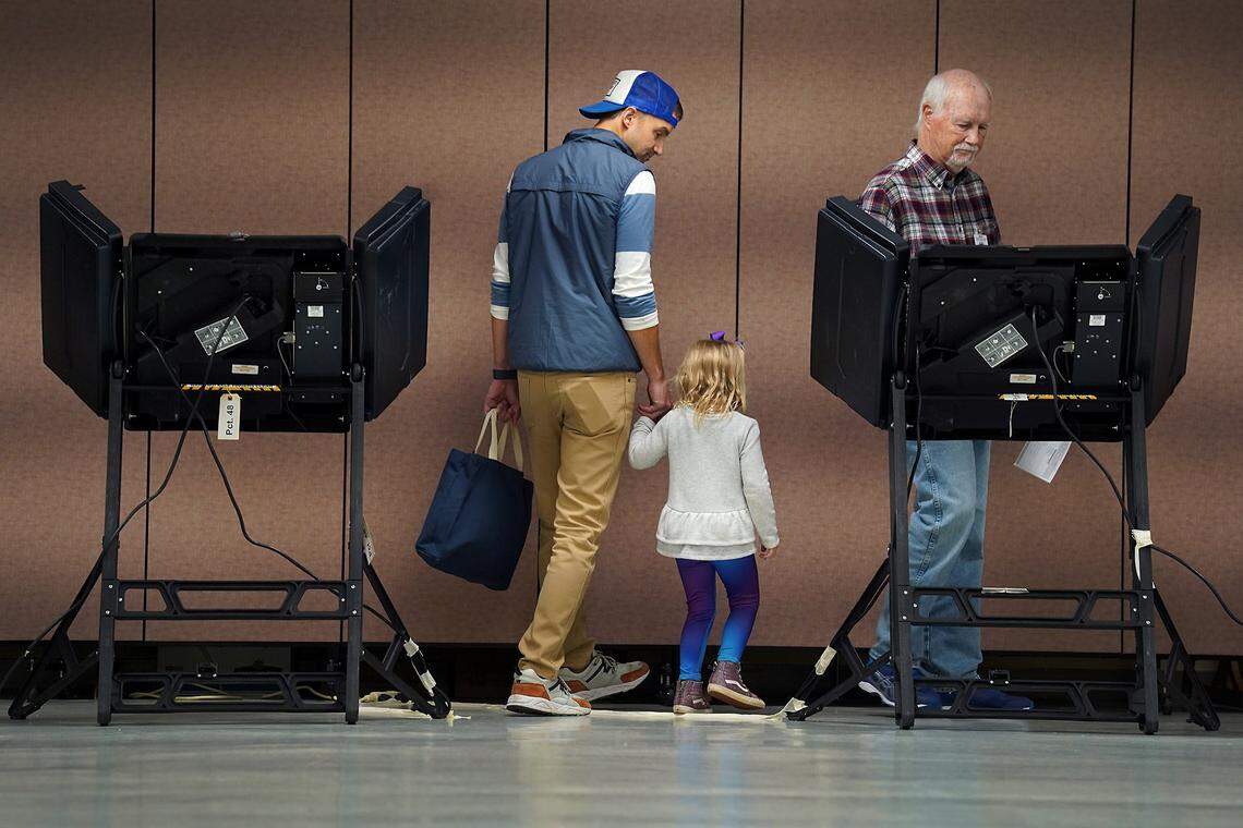 Josh Hughes, left and daughter, Ellie, 4, center, are led to a voting machine by precinct official Ed King, right, at Precinct #48 at Providence United Methodist Church in Charlotte, NC on Tuesday, November 5, 2019.
