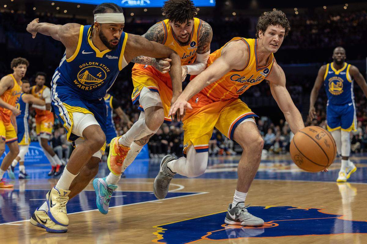 Golden State Warriors guard Moses Moody, left, Charlotte Hornets guard Lamelo Ball, center, Charlotte Hornets PJ Hall scramble for the ball at the Spectrum Center in Charlotte, N.C., on Wednesday, December 31, 2025.