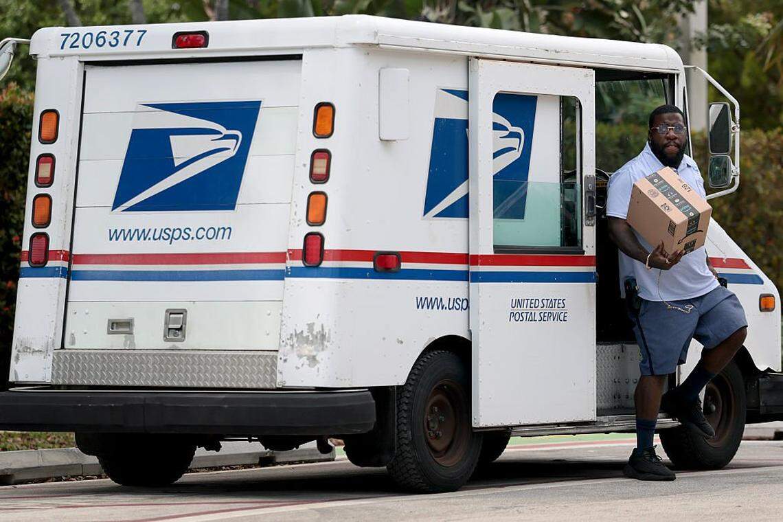 MIAMI, FLORIDA - MARCH 19: Postal carrier Marc Jacques delivers the mail in a neighborhood on March 19, 2026 in Miami, Florida. The head of the US Postal Service has warned lawmakers that it may run out of money in less than a year unless Congress allows it to borrow more money and charge more for postage. (Photo by Joe Raedle/Getty Images)