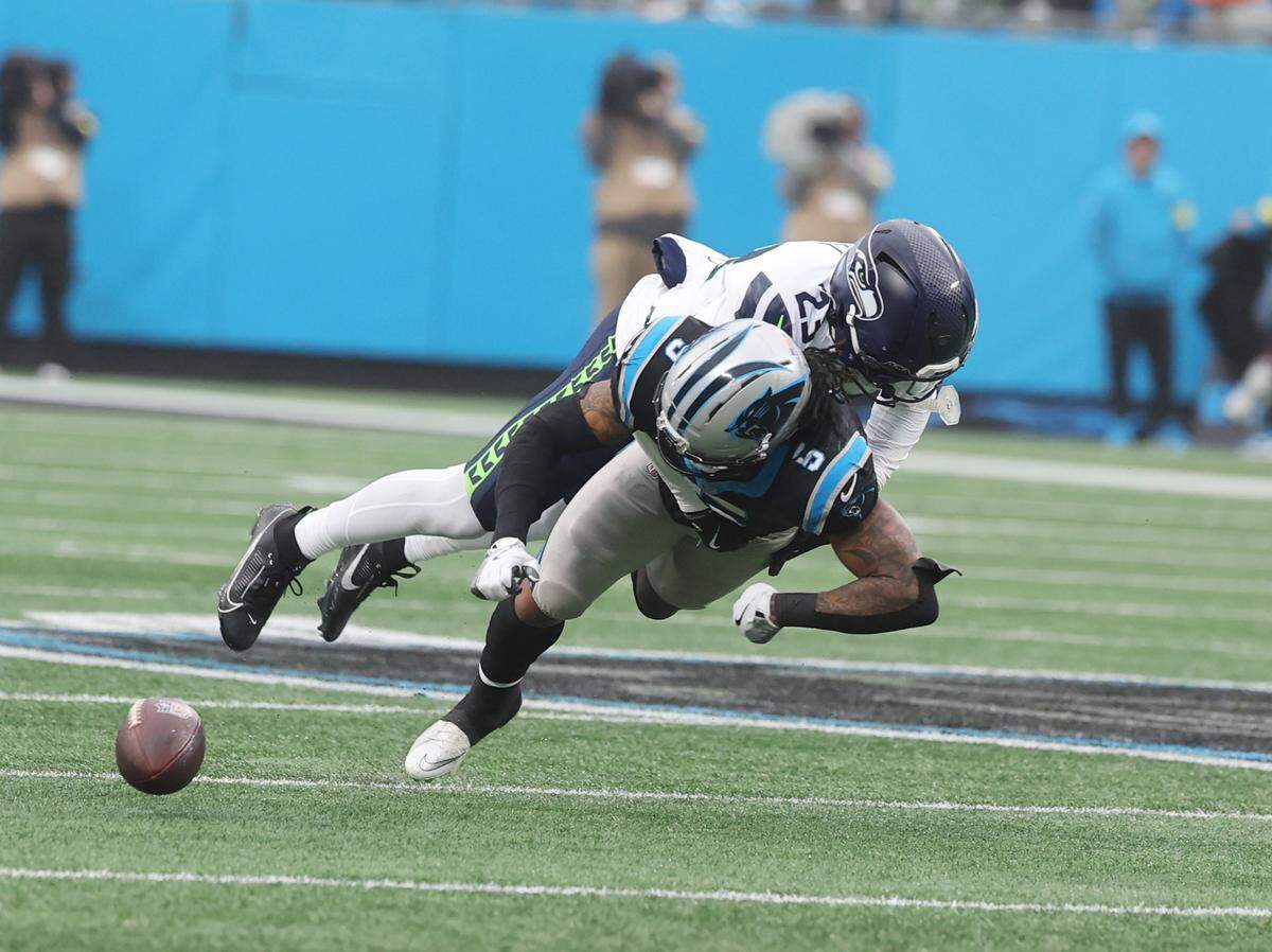 Carolina Panthers running back Rico Dowdle loses control of the ball as he is tackled by Seattle Seahawks safety D'Anthony Bell during a Dec. 28, 2025 game at Bank of America Stadium in Charlotte. Carolina lost 27-10.