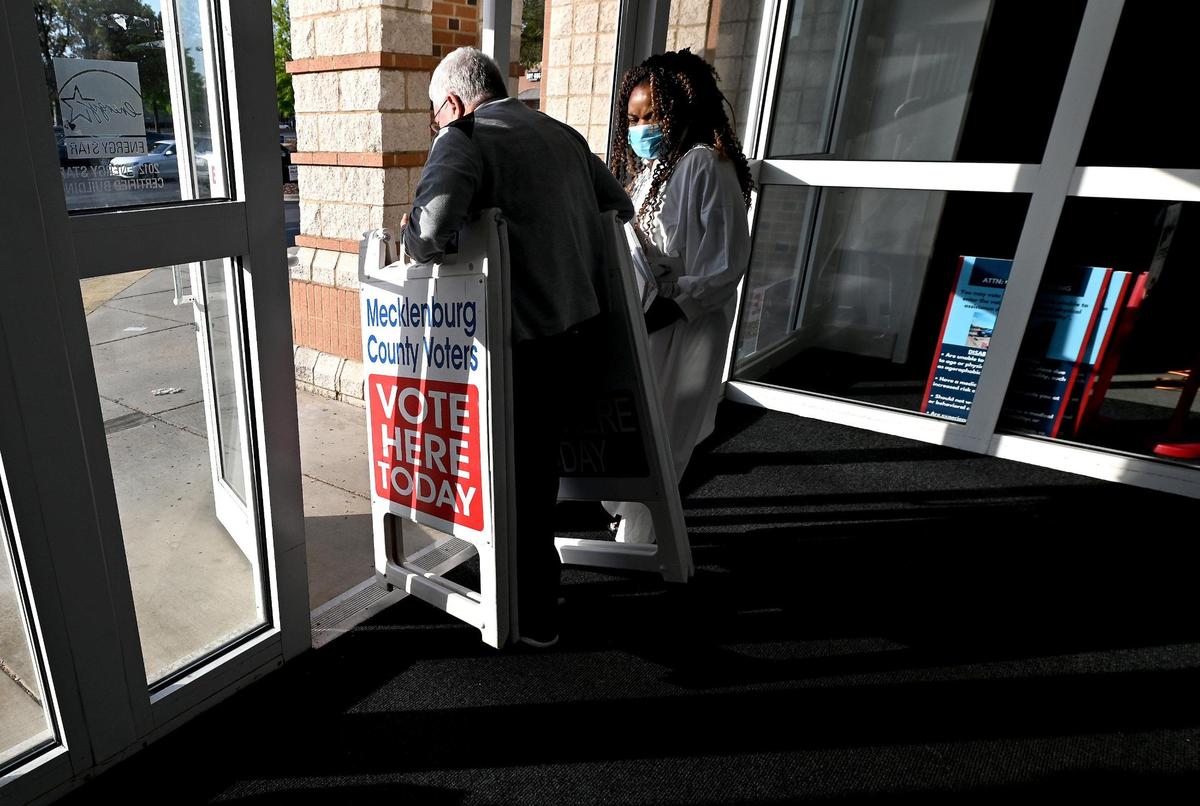 Site coordinator Brad Winter carries vote here signs into the parking lot to alert voters to stop. Early voting has started for the NC primaries on Thursday, April 28, 2022.