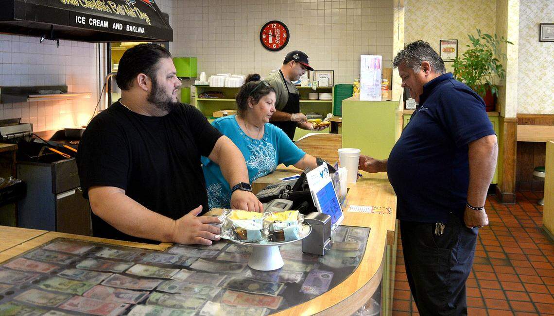 Nick Sikiotis, left, then 32, and his mother Joanna Sikiotis, then 62, center, serve customers at Green’s Lunch in Charlotte in 2022.