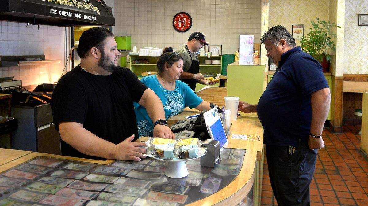Nick Sikiotis, left,, 32 and his mother Joanna Sikiotis, 62, center, serve customers at the Green’s Lunch in Charlotte on Thursday. The Green’s Lunch, nestled in uptown Charlotte on West 4th Street, is a nearly 100-year old business that is struggling with labor shortages and higher prices on everything from ingredients to cutlery.