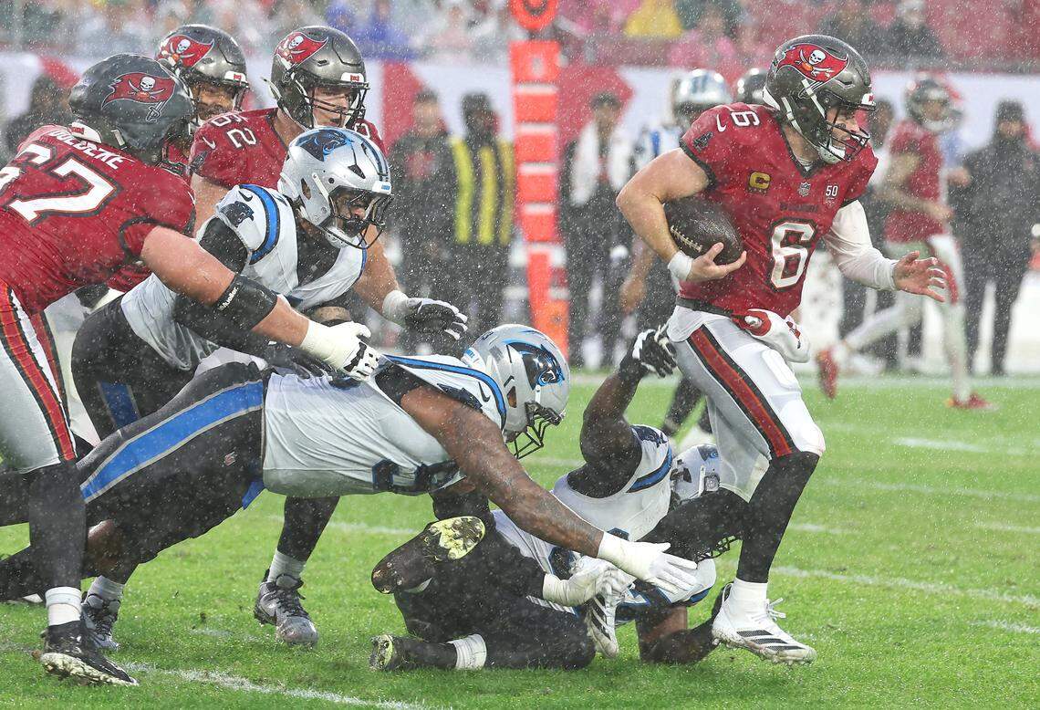 The Carolina Panthers defense is unable to make the tackle on Tampa Bay Buccaneers quarterback Baker Mayfield, right, as he rushes for yardage during action at Raymond James Stadium in Tampa, FL. on Saturday, January 3, 2026. The Buccaneers defeated the Panthers 16-14.