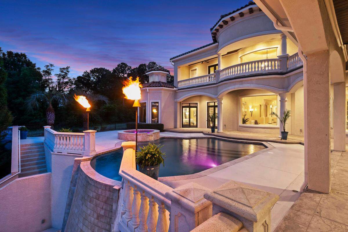 Outside the mansion are covered verandas with wood-paneled ceilings, a fireplace and dining spaces, multiple terraces, a custom pool and spa and a cascading waterfall that flows into a lower plunge pool.