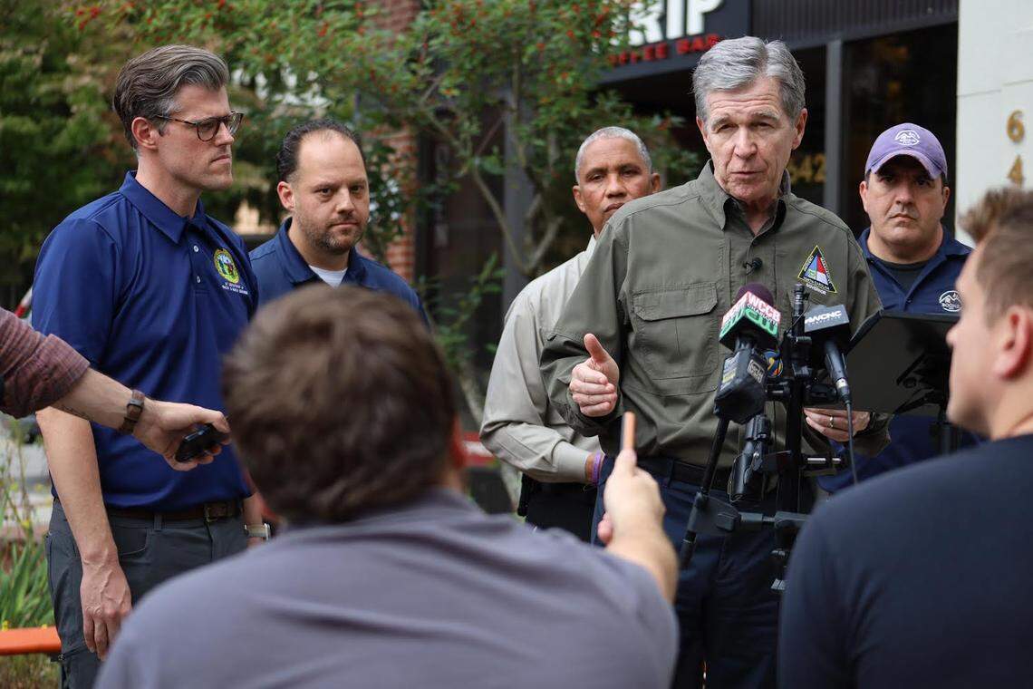 Journalist Moss Brennan (in foreground, back turned) asks a question of North Carolina governor Roy Cooper in the aftermath of Hurricane Helene.