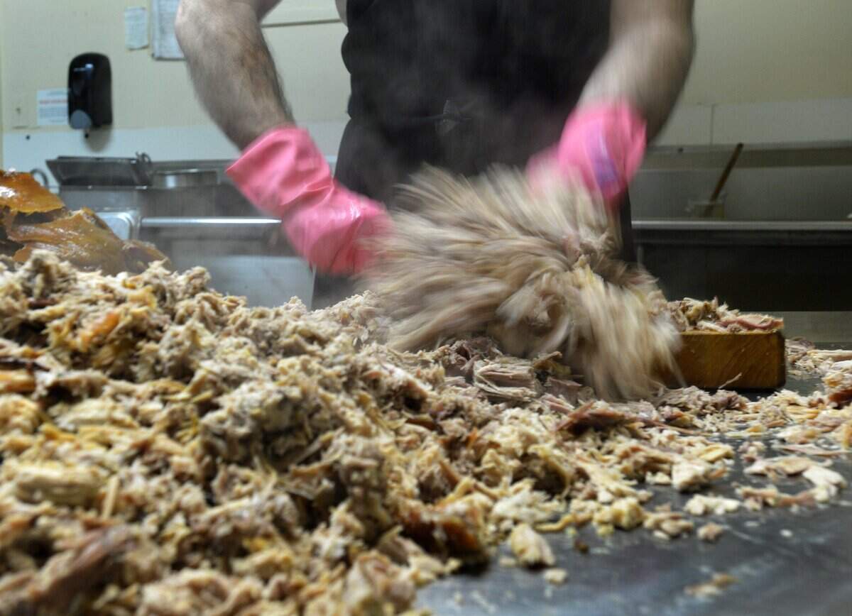 Steve Spoon chops fresh cooked pork before dawn at Bill Spoon’s Barbecue in 2012. The restaurant closed in 2020.