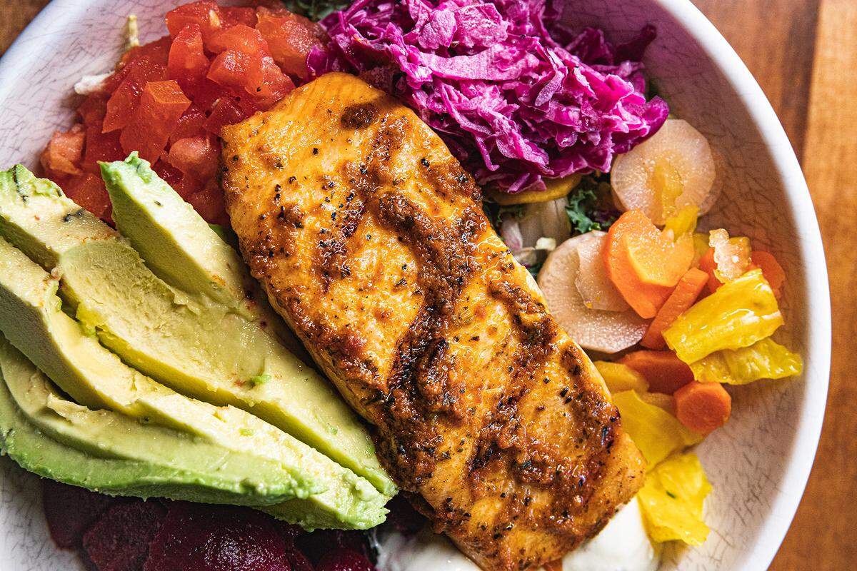 A bowl with Harissa Salmon and vegetables at YAFO Kitchen.