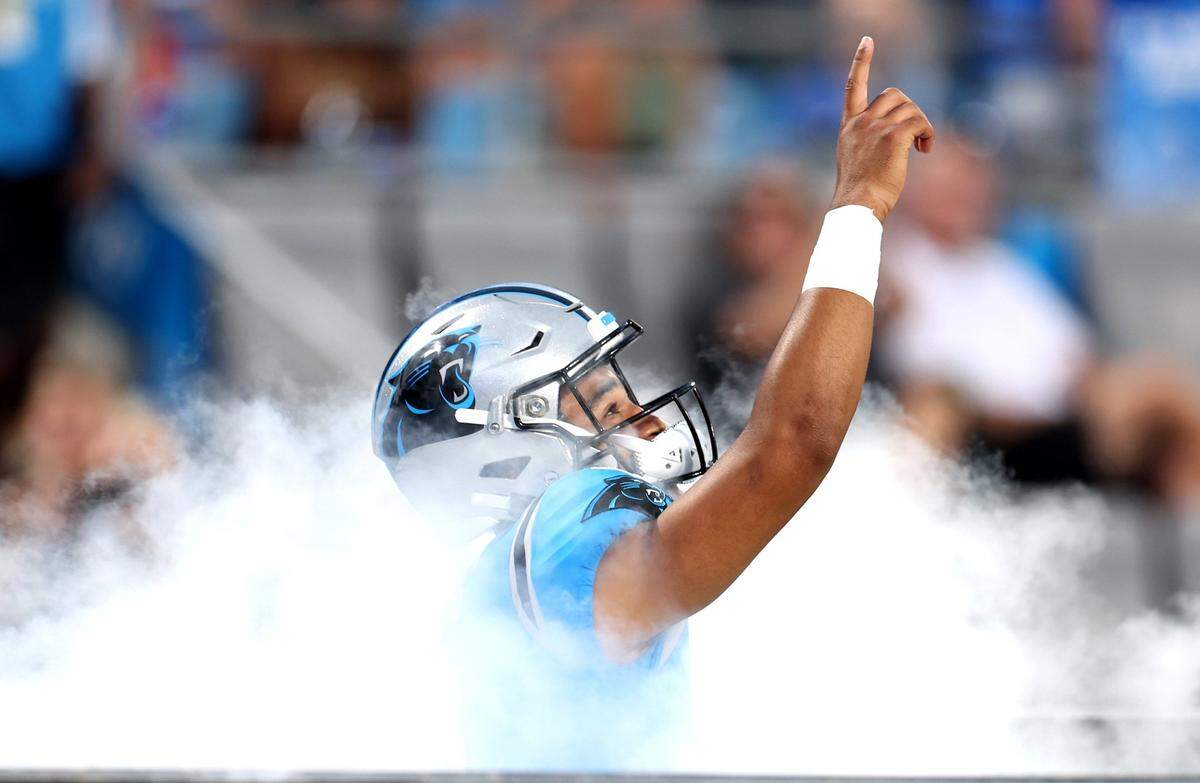 Carolina Panthers quarterback Bryce Young points skyward as he runs through the smoke onto the Bank of America Stadium field during player introductions on Friday, August 25, 2023.