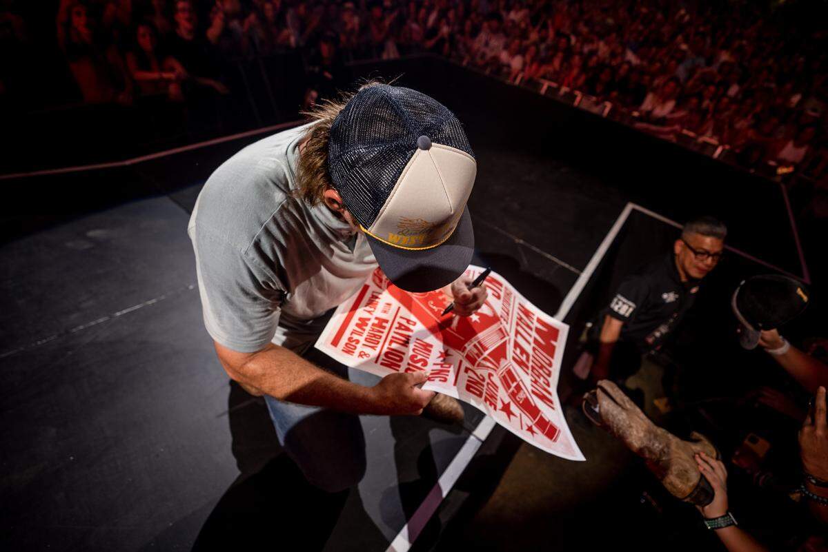 Morgan Wallen signs a concert poster for a fan during his “Dangerous Tour” on Thursday night at PNC Music Pavilion.