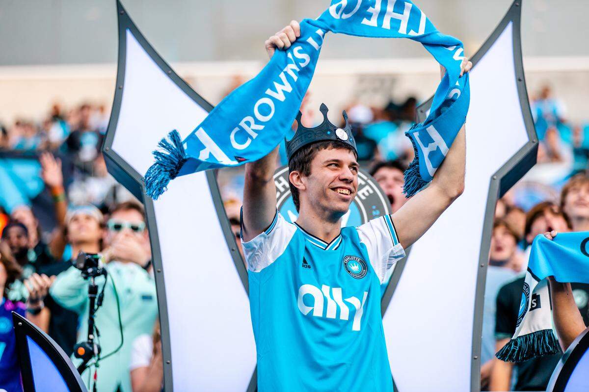 Zach Burkholder smiles and cheers with the Charlotte FC supporters as he is crowned and honored before the team’s game on May 17, 2023, at Bank of America Stadium.