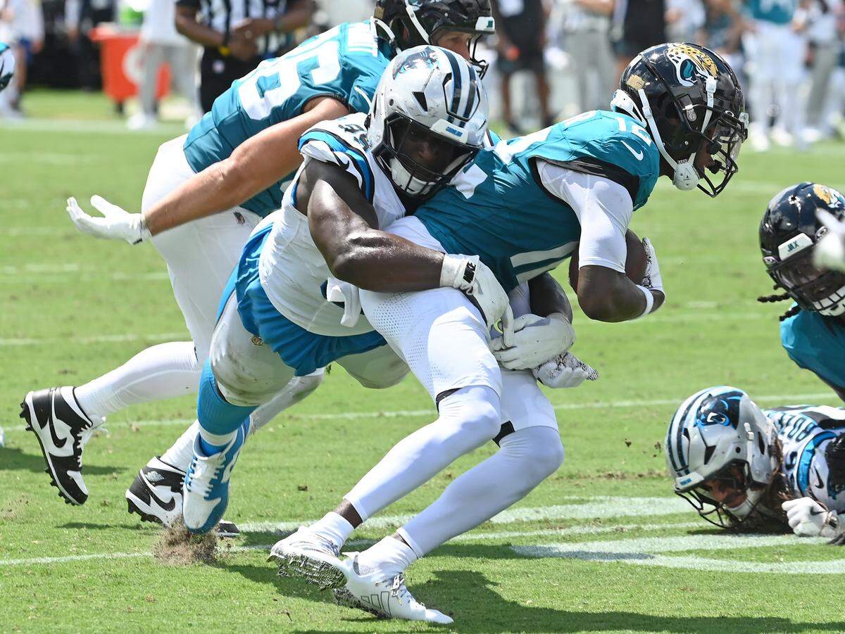 Carolina Panthers defensive tackle Turk Wharton, left, looks to make the tackle on Jacksonville Jaguars wide receiver Travis Hunter, right, during action on Sunday, September 7, 2025 at Everbank Stadium in Jacksonville, Florida.