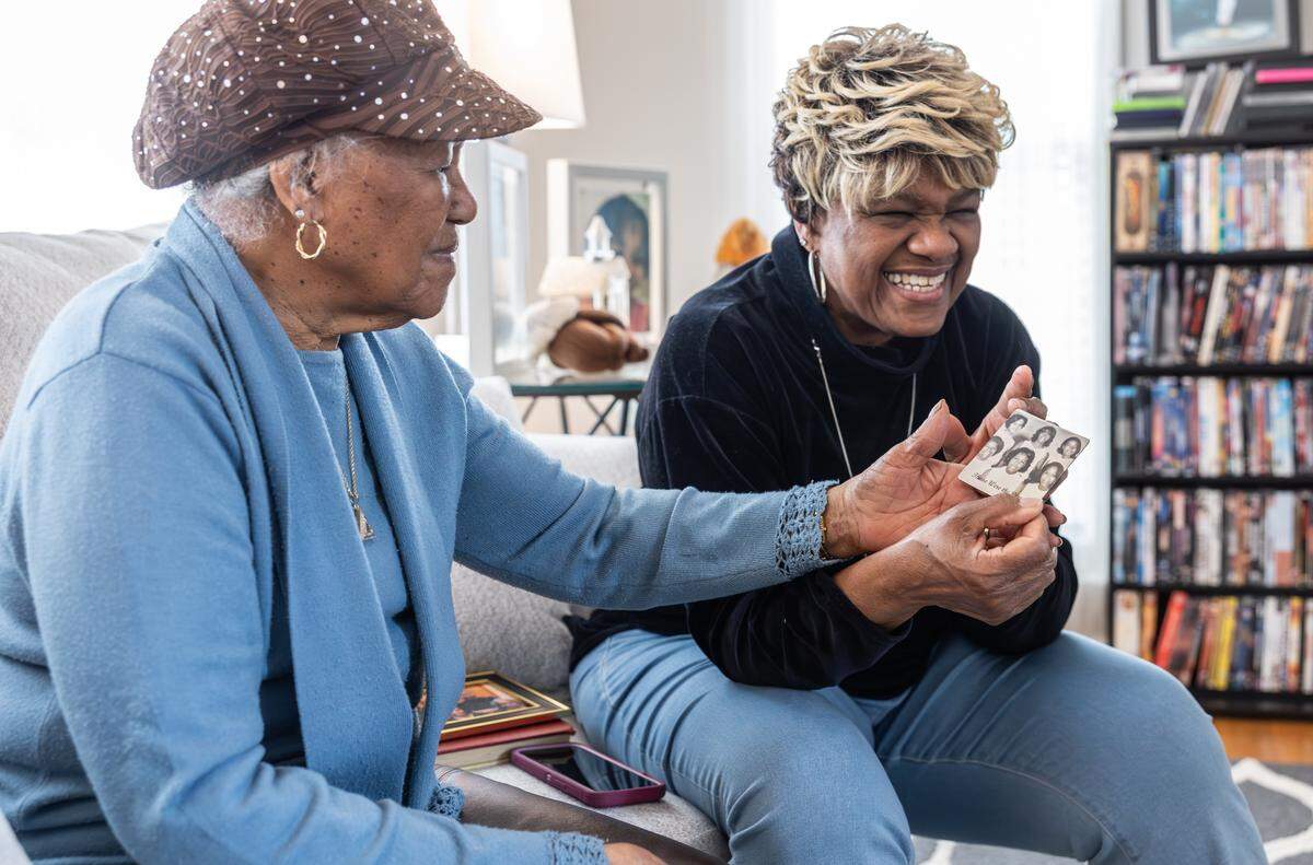 Esther Carter-Buie, left, and her daughter Gwen Carter-Adamson share a laugh as they look at a photo of Gwen and her friends when they were young in High Point, N.C., on Friday, March 20, 2026. 