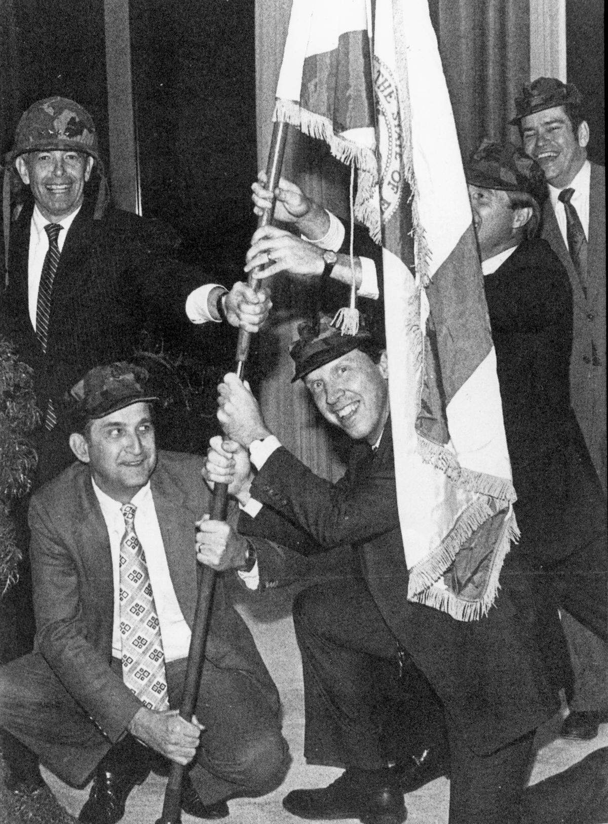 Posing victoriously with the flag of Florida are Hugh McColl, left, Paul Polking, Joe Martin, Mark Leggett and Frank Gentry. The North Carolina National Bank executives posed for the photo in 1981 as they awaited regulatory approval for their purchase of the First National Bank of Lake City.