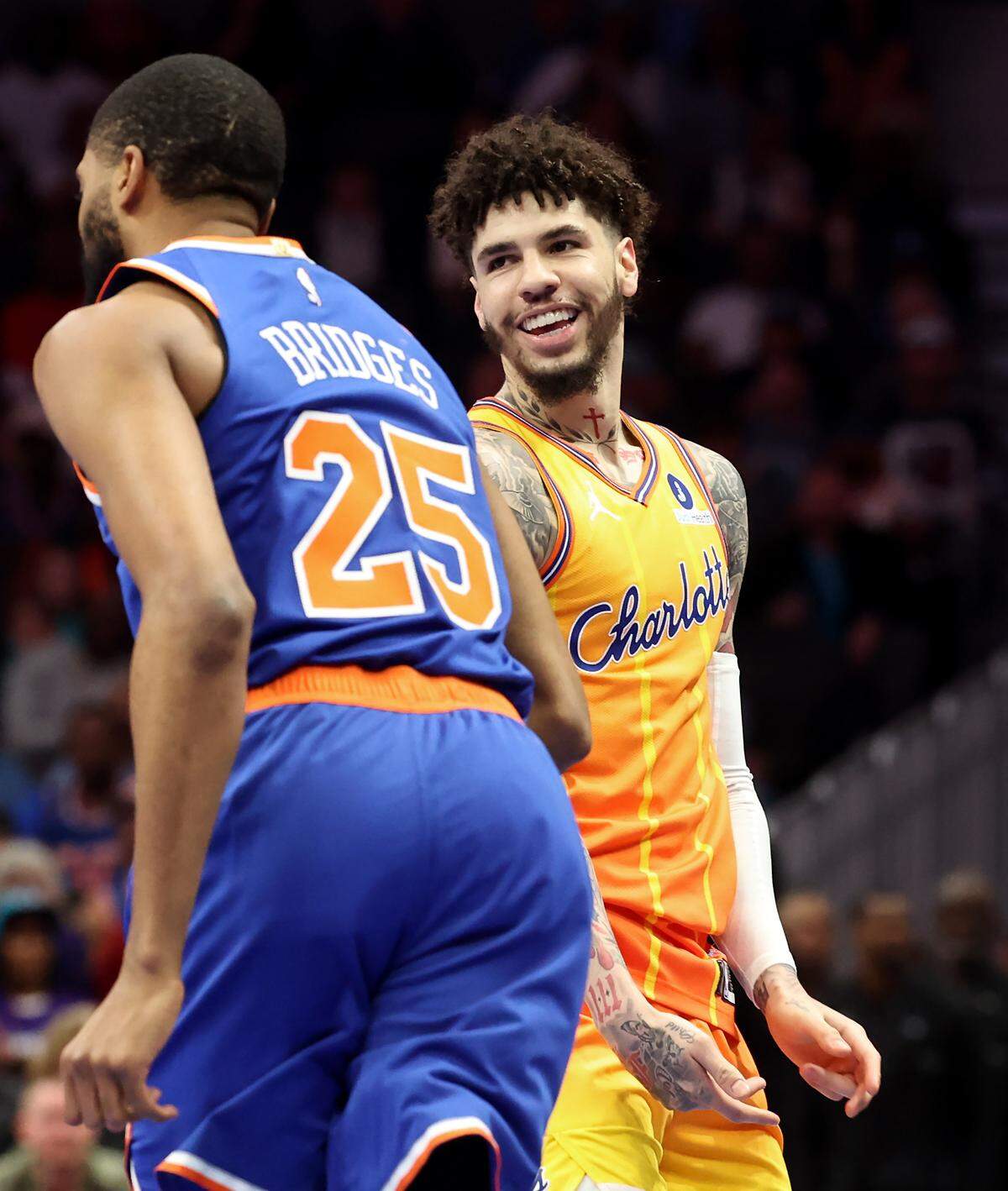 Charlotte Hornets guard LaMelo Ball, right, smiles after hitting a three-point shot over New York Knicks guard/forward Mikal Bridges, left, during action at Spectrum Center in Charlotte, North Carolina, on Thursday, March 26, 2026. 