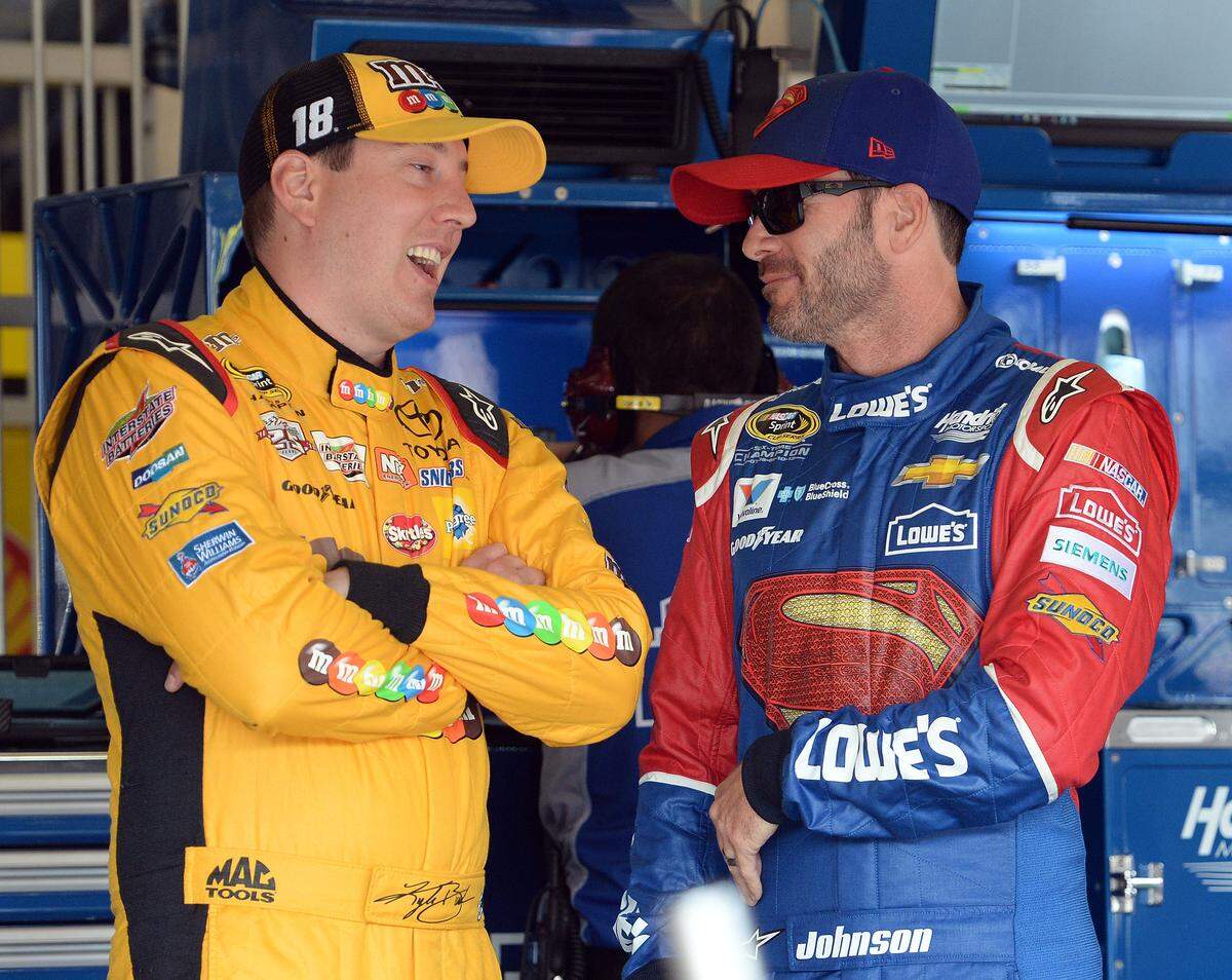 Kyle Busch, left, speaks with Jimmie Johnson in the garage area prior to the opening practice session Friday, March 18, 2016, for the NASCAR auto race at Auto Club Speedway in Fontana, Calif. (AP Photo/Will Lester)