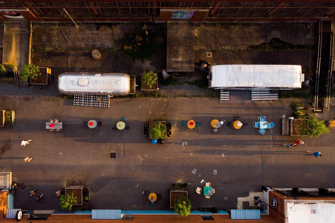 People walk by Airstream trailers that have been converted into offices and shops along the Boileryard at Camp North End.