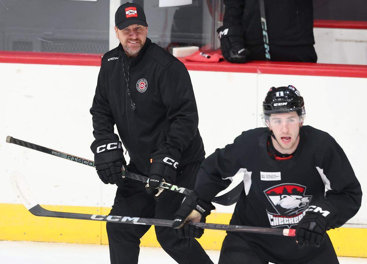 Charlotte Checkers head coach Geordie Kinnear, left, smiles as he watches his team run through drills during practice at BoJangles Coliseum in Charlotte, NC on Thursday, October 9, 2025.