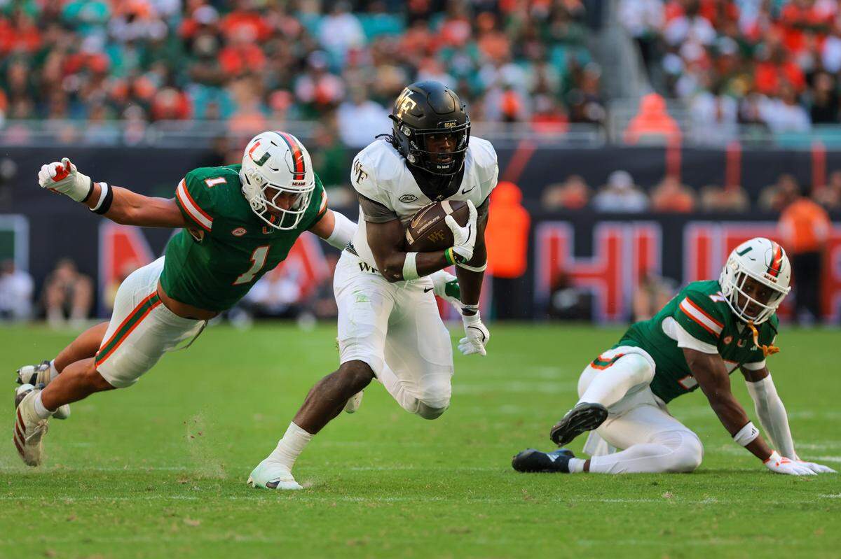 Wake Forest running back Demond Claiborne runs past Miami Hurricanes linebacker Francisco Mauigoa (1) during a 2024 game at Hard Rock Stadium in Miami Gardens, Florida. 