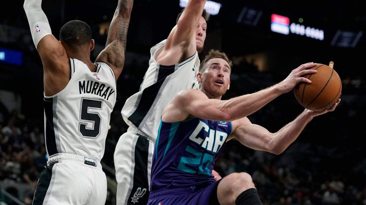 Charlotte Hornets forward Gordon Hayward (20) drives to the basket ahead of San Antonio Spurs guard Dejounte Murray (5) and forward Drew Eubanks (14) during the first half of an NBA basketball game, Wednesday, Dec. 15, 2021, in San Antonio. (AP Photo/Eric Gay)
