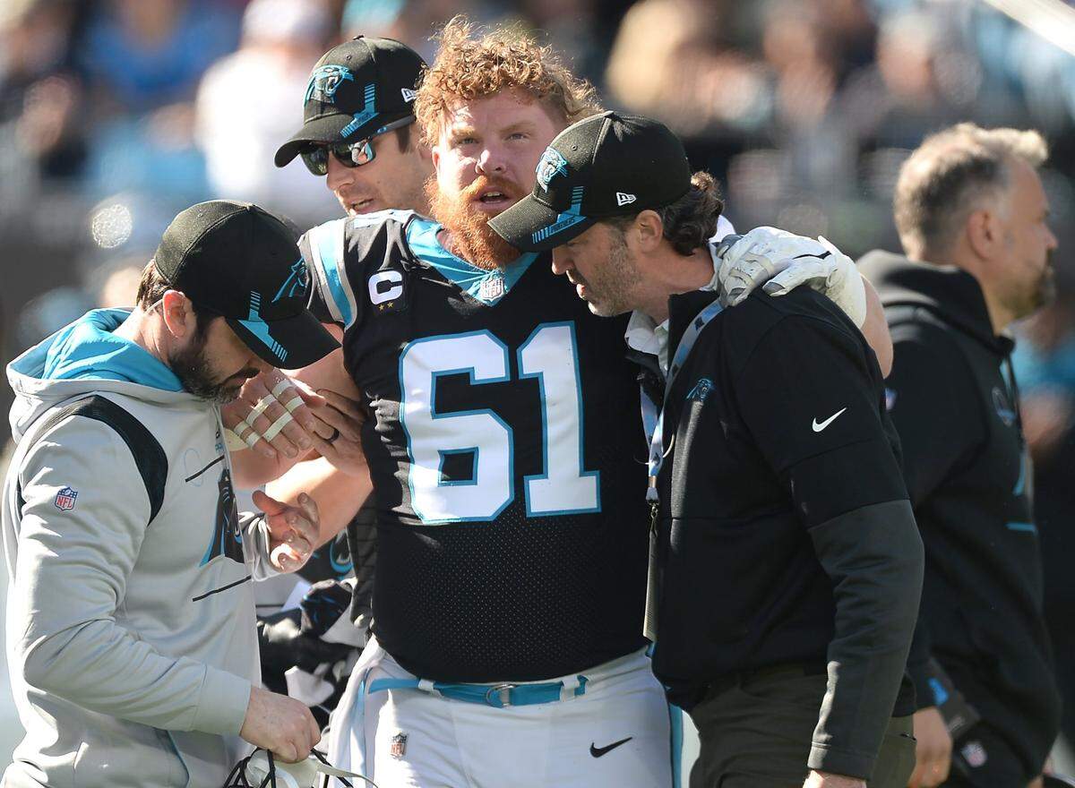 Carolina Panthers center Matt Paradis, center, is helped off the field by team personnel during first quarter action against the New England Patriots at Bank of America Stadium in Charlotte, NC on Sunday, November 7, 2021. 