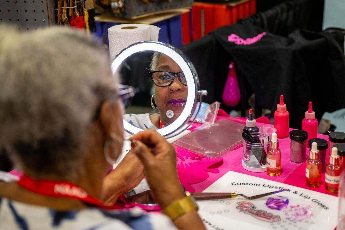 NAACP attendee Sharonda Johnson tries on her custom made lipstick from vender Lip Print Beauty Bar at the NAACP convention in Charlotte Saturday, July 12, 2025.
