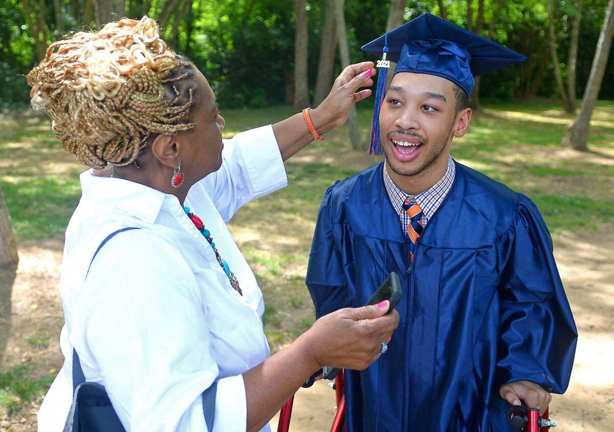 Saundra Adams, left, adjusts the 2021 tassel on Chancellor Lee Adams’ graduation mortarboard on Monday. Chancellor Lee will be graduating from Vance High School in June. He is the son of Cherica Adams and former Carolina Panthers wide receiver Rae Carruth.