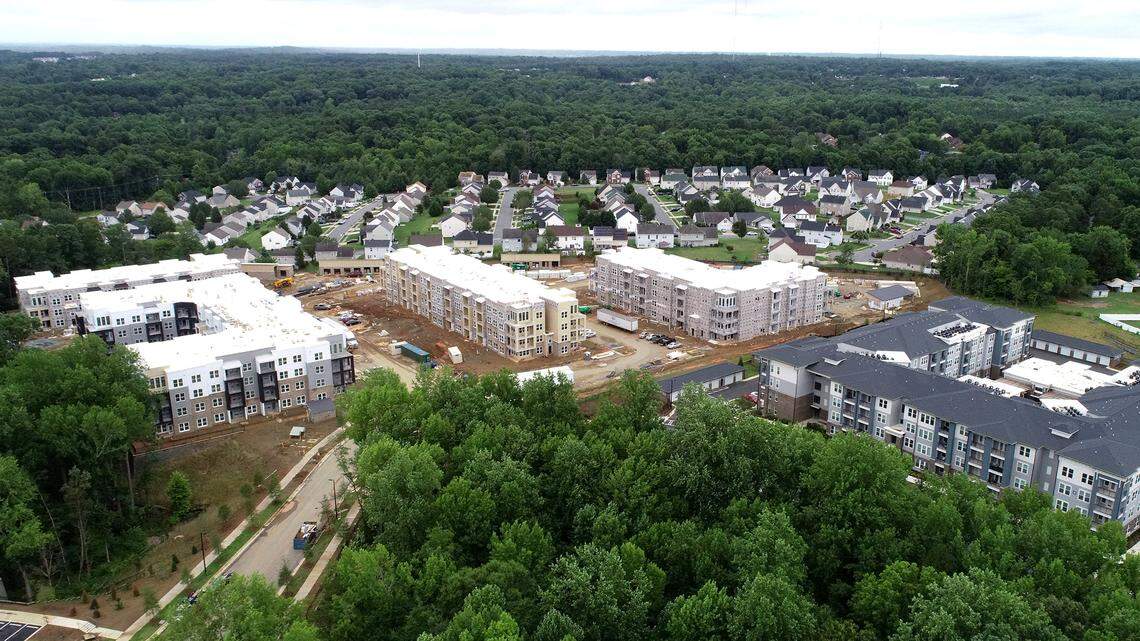 The Tapestry University City apartments development rises in front of the homes in Rocky River Village in the University City area of Charlotte, on July 8, 2021. Tapestry University City is a luxury apartment community.