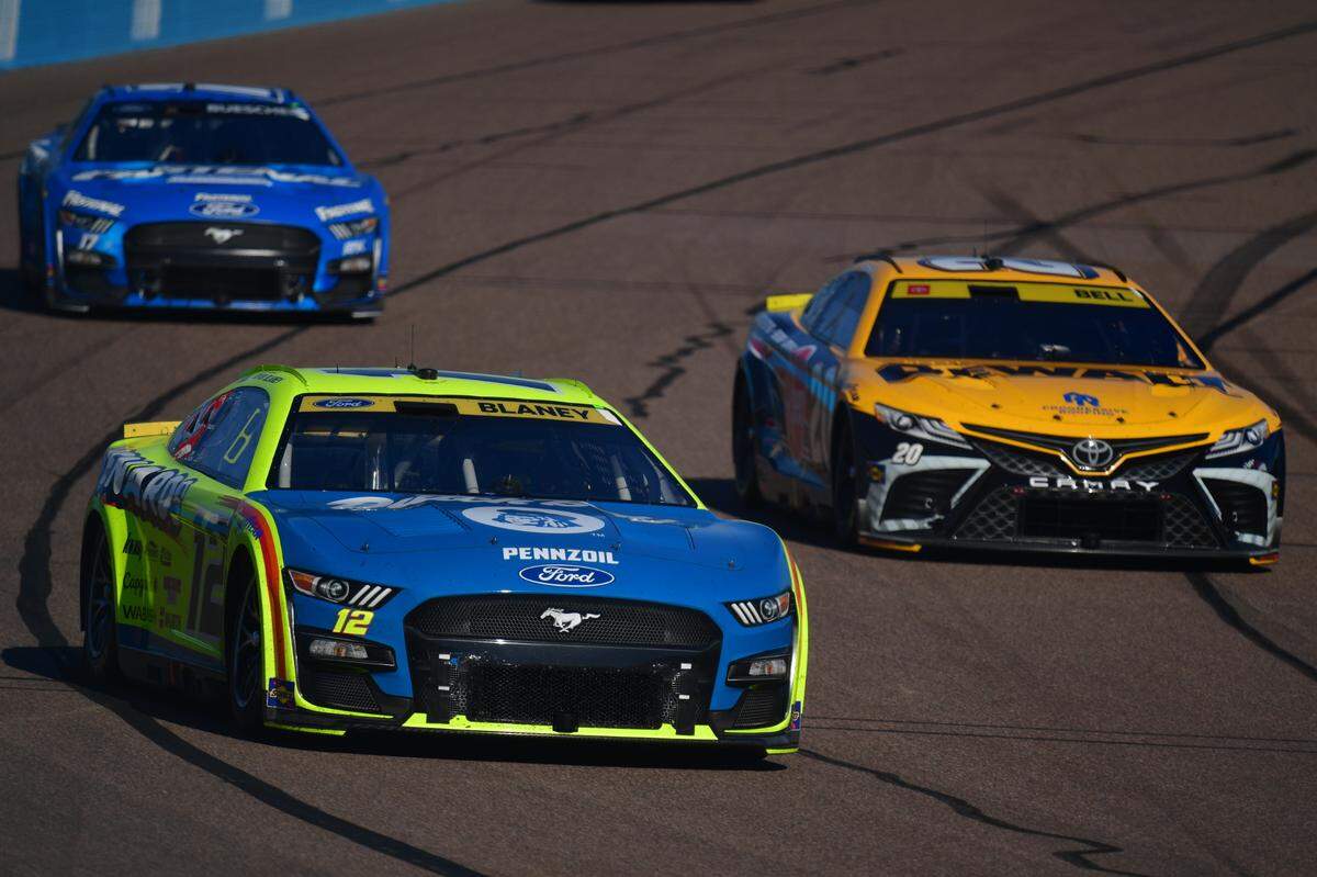 Nov 5, 2023; Avondale, Arizona, USA; NASCAR Cup Series driver Ryan Blaney (12) races for position against driver Christopher Bell (20) during the Cup Series Championship race at Phoenix Raceway. Mandatory Credit: Gary A. Vasquez-USA TODAY Sports
